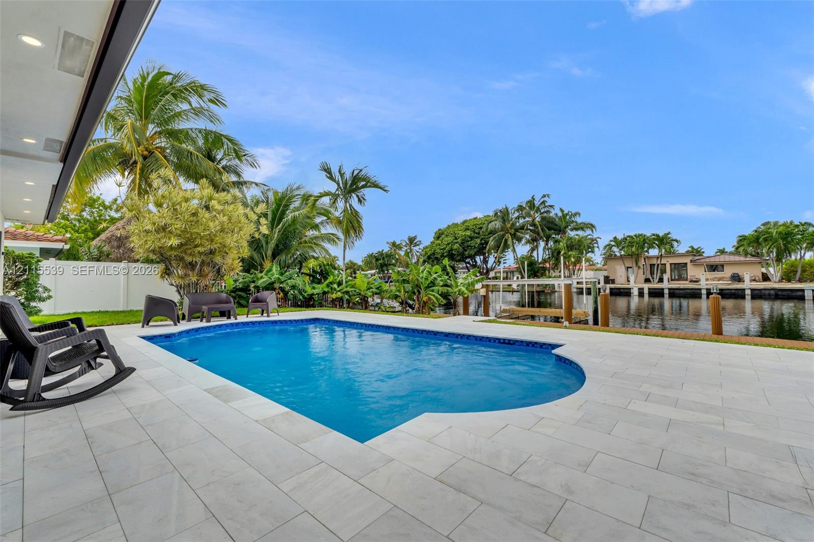 Inground swimming pool with tiled surround, concrete patio, and direct waterfront access via a private dock
