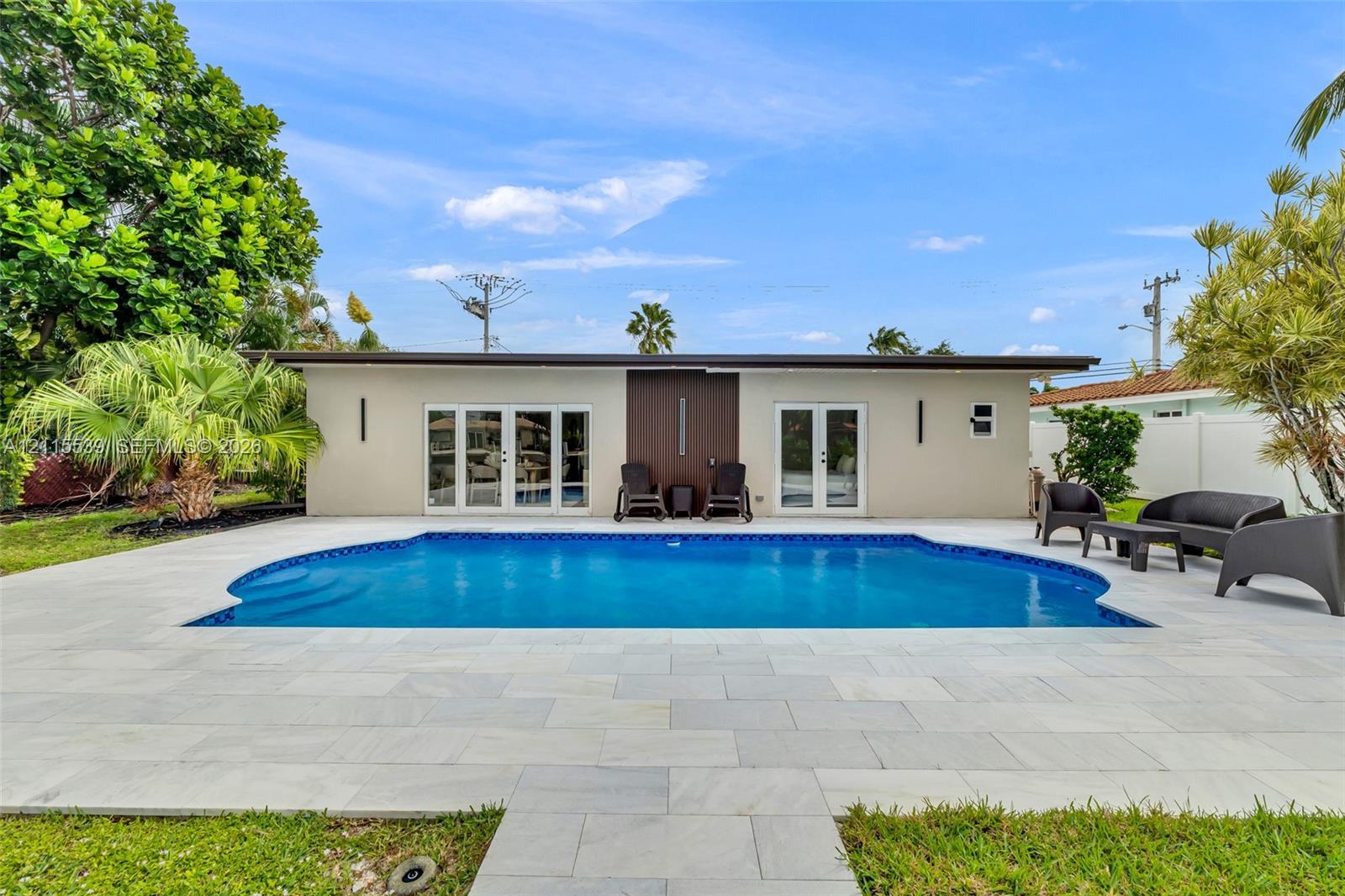 Backyard swimming pool featuring a light-toned stone deck, integrated stair entry, and dual sets of glass-paneled double doors