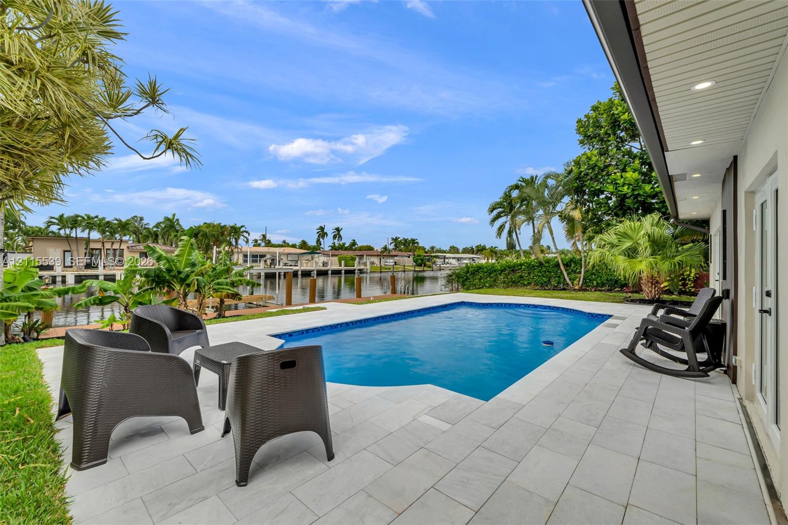 Waterfront swimming pool with a stone paver deck and a recessed soffit featuring integrated lighting
