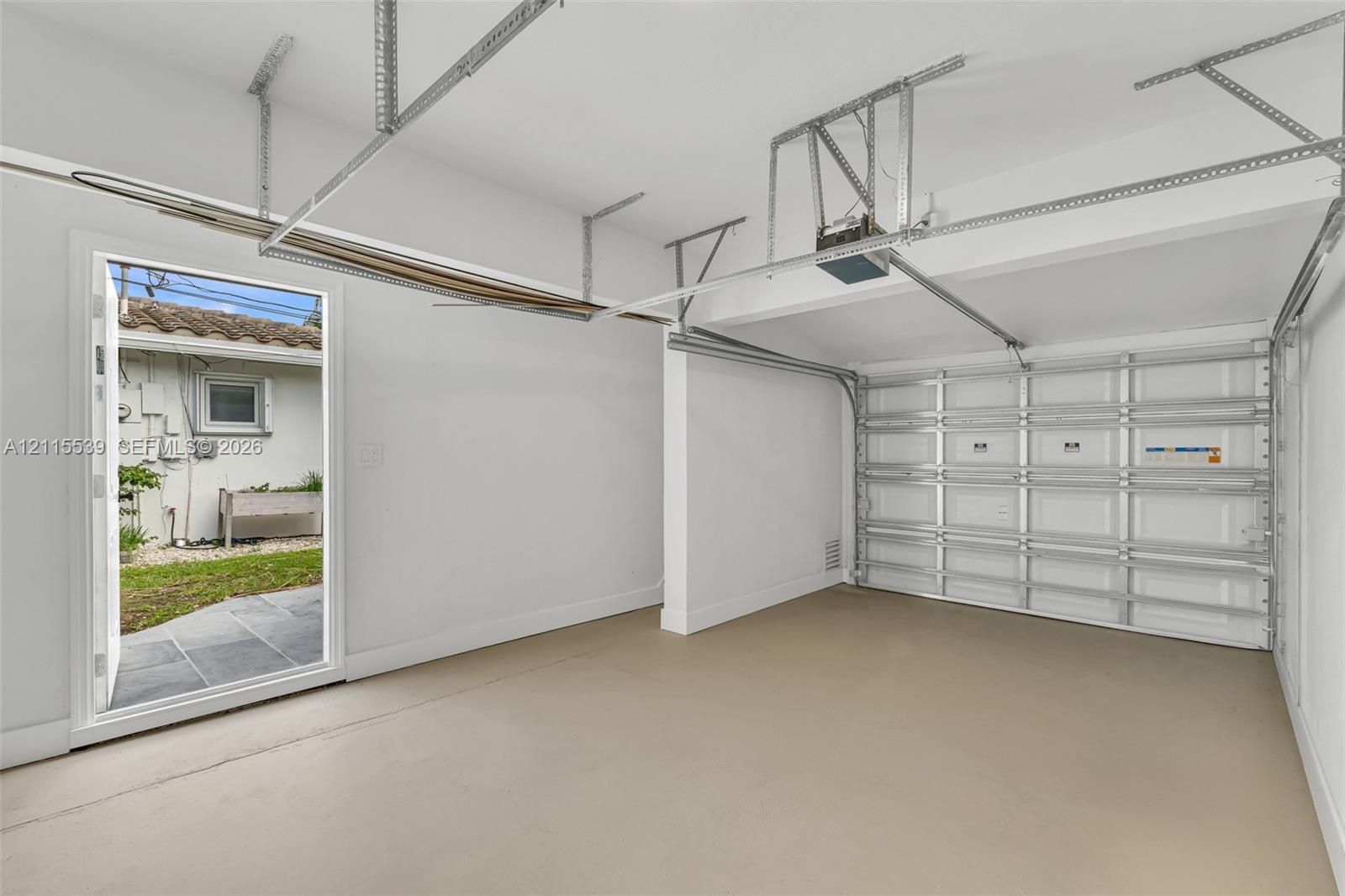 Two-car garage featuring a sectional overhead door, painted concrete flooring, white walls, and a dedicated exterior side-entry door