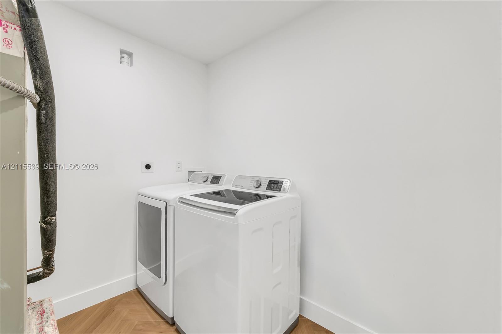 Laundry area featuring wood-finish herringbone flooring and white walls
