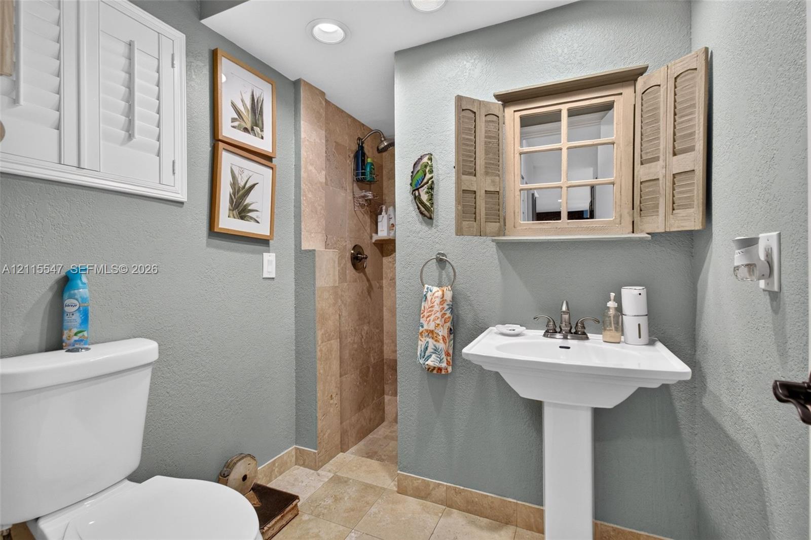 Pedestal sink with metal faucet, tile-surround walk-in shower, stone-finish flooring, and recessed ceiling lighting