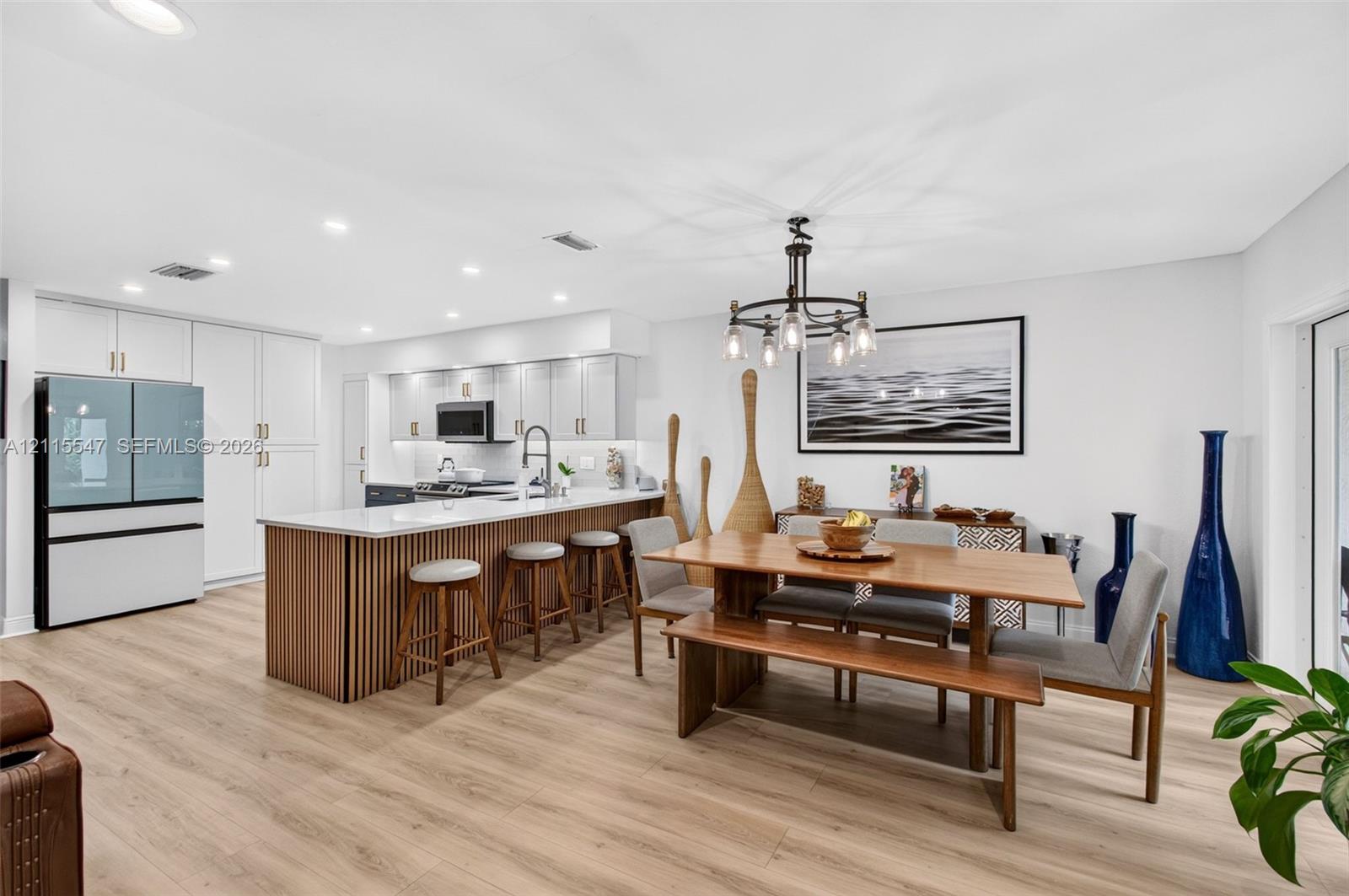 Kitchen featuring white shaker-style cabinetry, wood-slat kitchen island with a white countertop, recessed lighting, chandelier, and wood-finish flooring