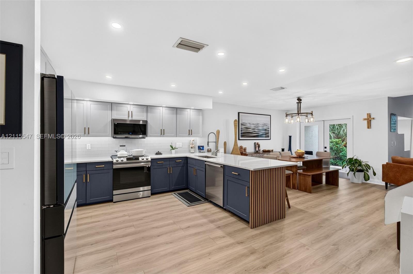 Kitchen featuring two-tone cabinetry, wood-finish flooring, quartz countertops, a slatted wood kitchen island accent, and recessed lighting