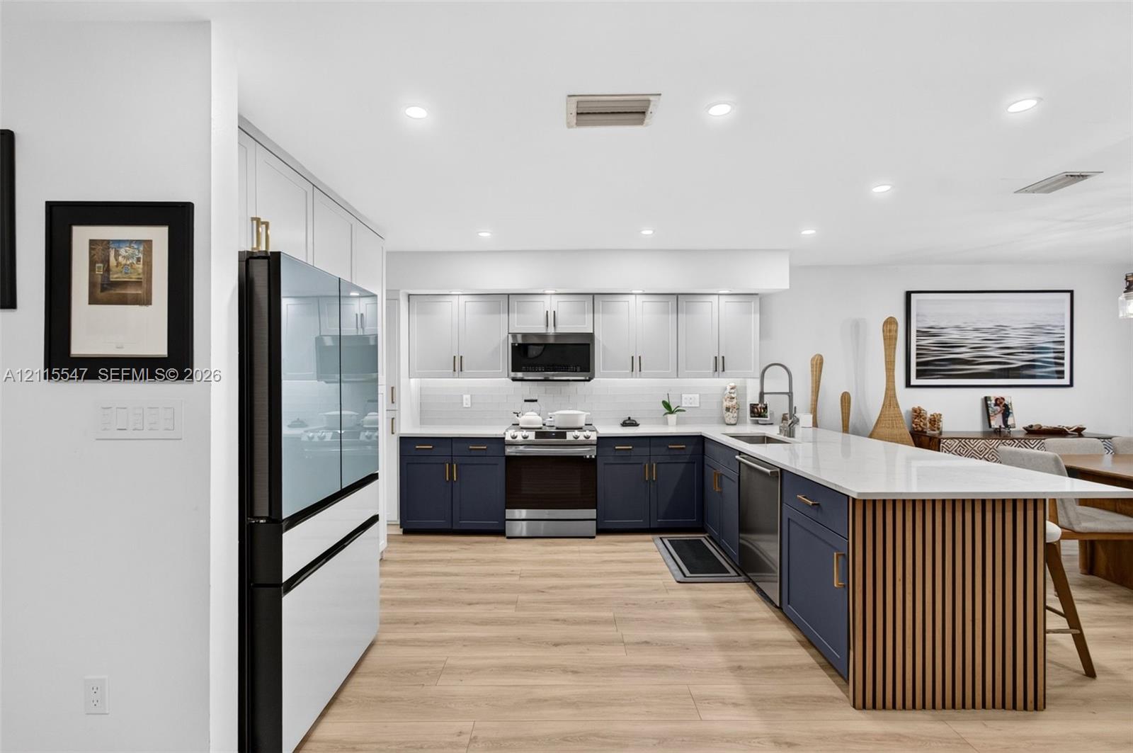 Kitchen featuring two-tone cabinetry, wood-finish flooring, recessed lighting, stone countertops, and a wood-slat kitchen island facade