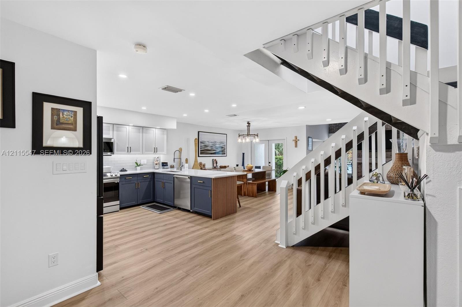 Kitchen featuring two-tone cabinetry, wood-finish flooring, recessed lighting, and a staircase with a white balustrade
