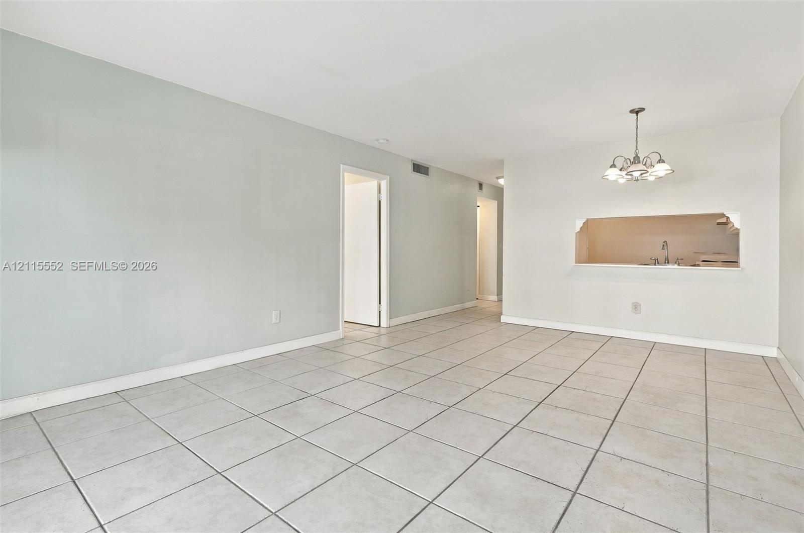 Ceramic tile flooring, neutral wall tones, multi-arm chandelier, and a cut-out wall opening