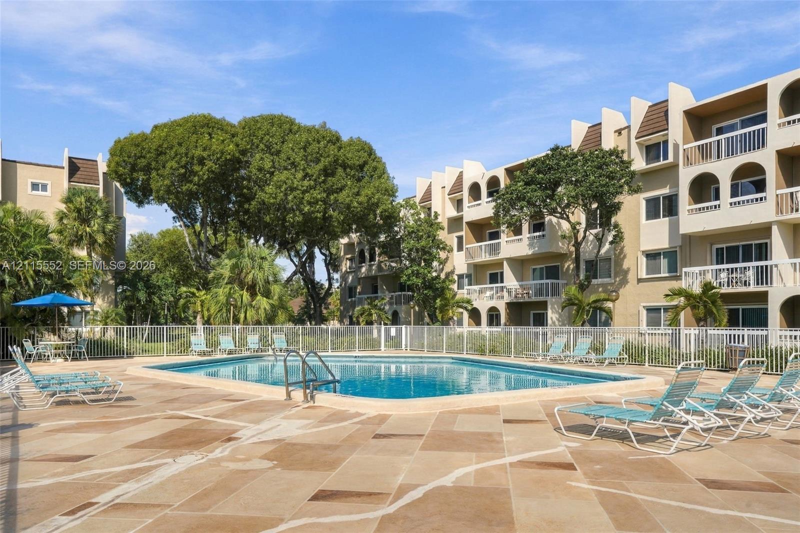 In-ground swimming pool featuring a concrete deck, perimeter fencing, and mature landscaping