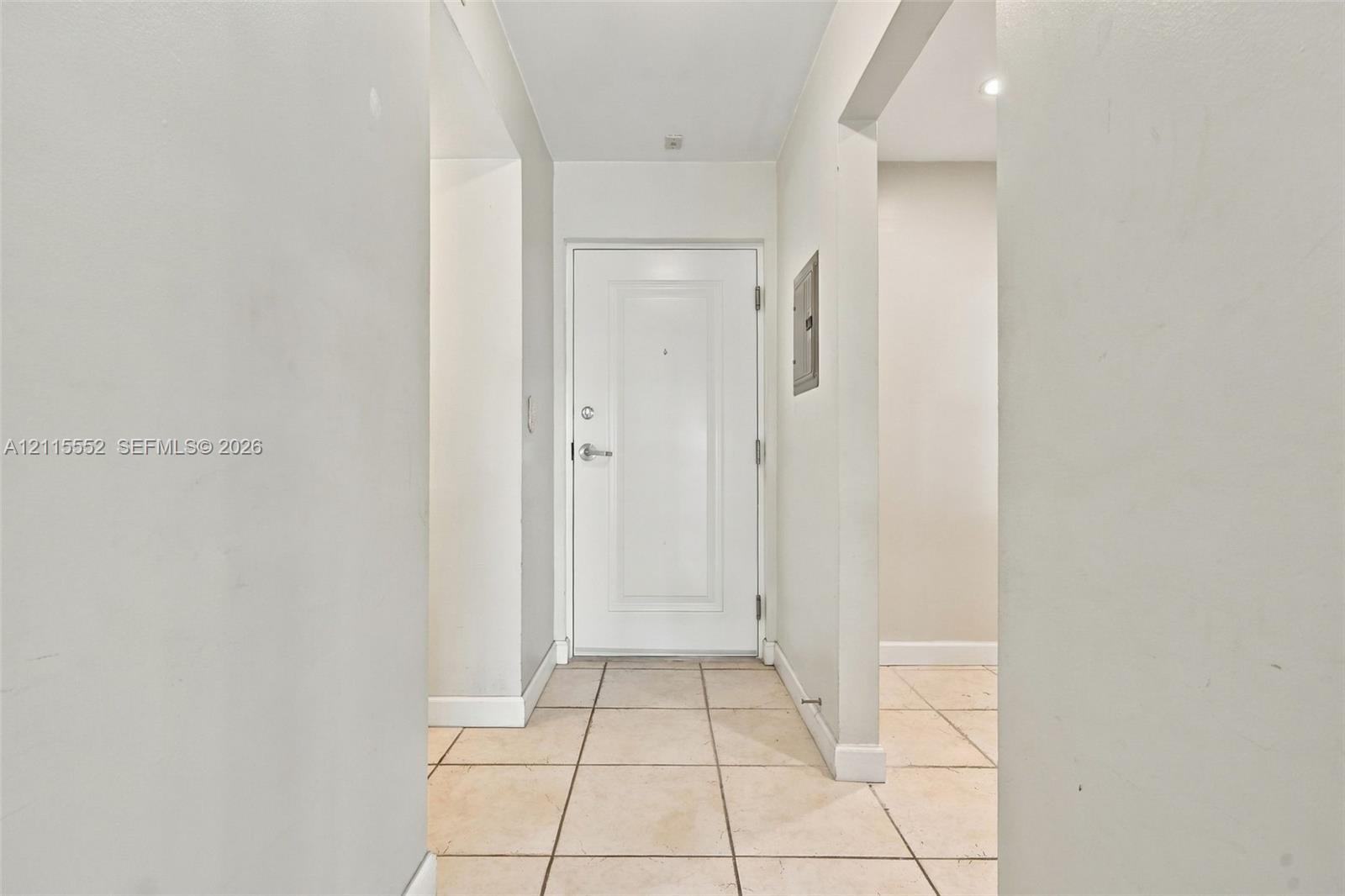Entryway featuring a white paneled door with brushed metallic hardware and light-toned ceramic tile flooring
