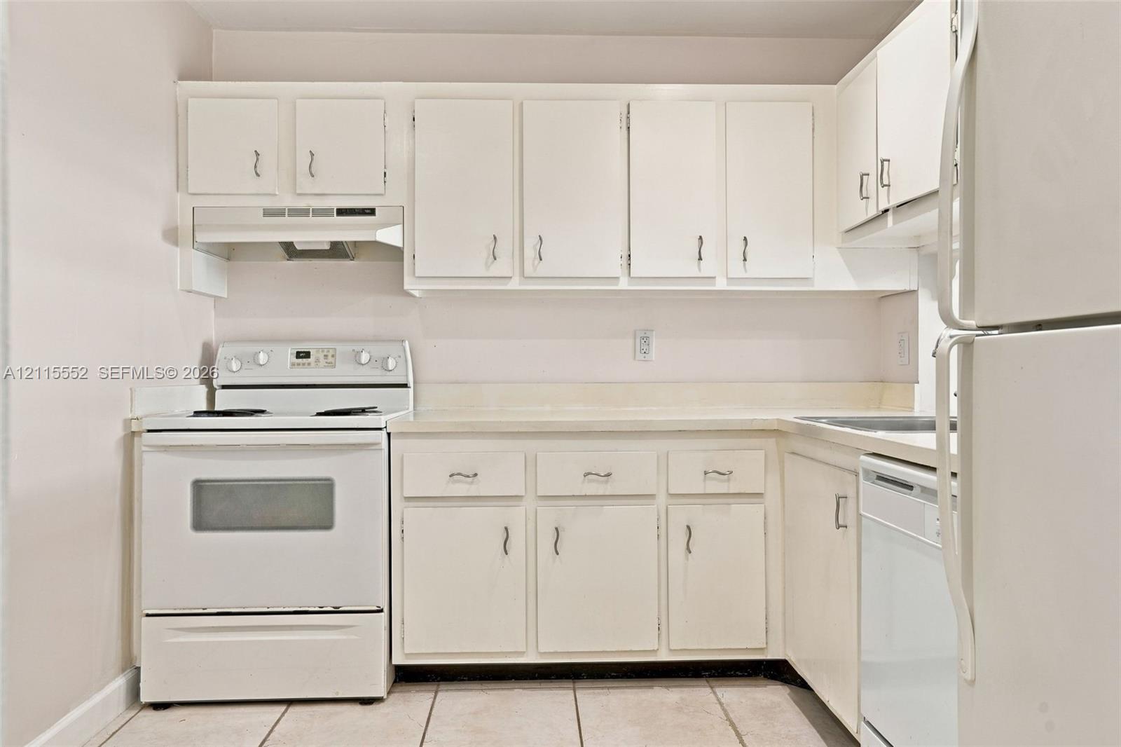 Kitchen featuring white cabinetry, a neutral solid-surface countertop, tiled flooring, and integrated white appliances including a range, range hood, and dishwasher