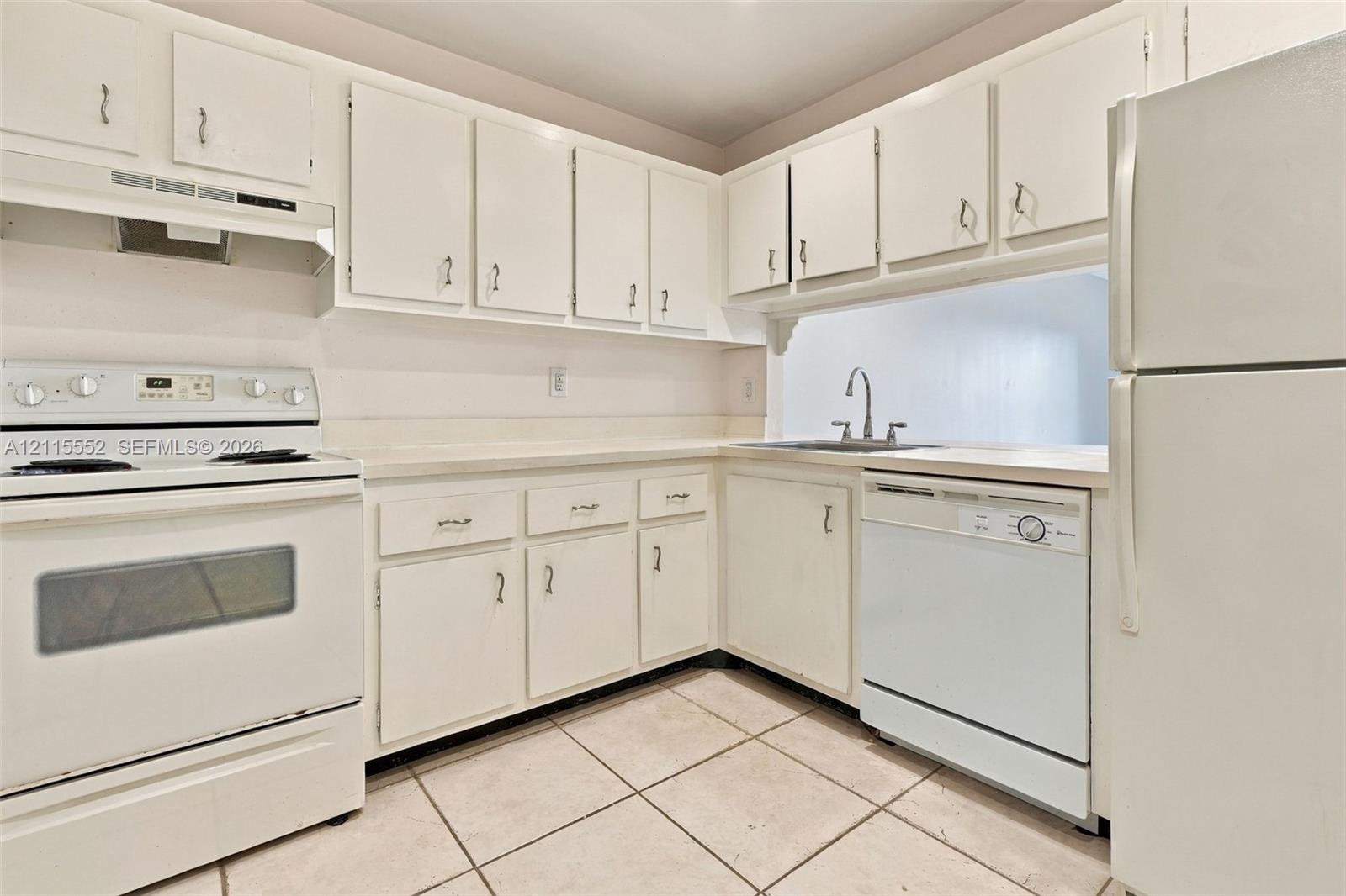 Kitchen featuring white cabinetry, solid-surface countertops, tile flooring, and integrated white appliances including a range, dishwasher, and refrigerator