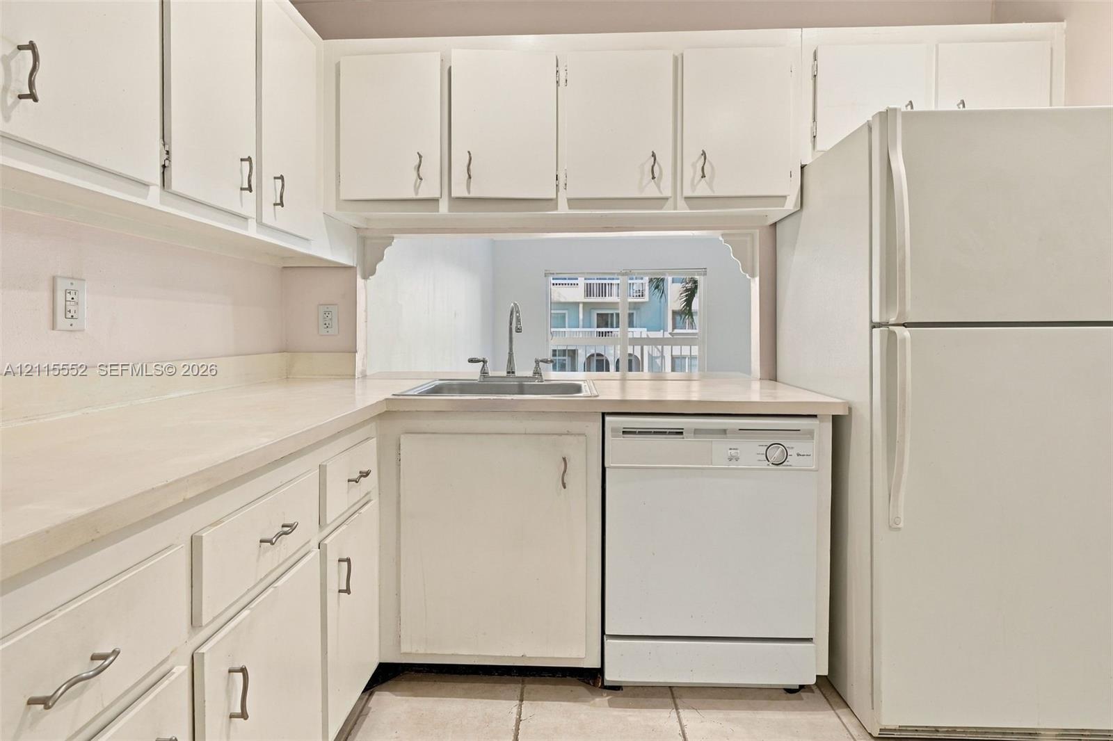 Kitchen featuring white cabinetry with brushed metal hardware, solid-surface countertops, a stainless steel sink with a goose-neck faucet, a built-in dishwasher, and a top-freezer refrigerator