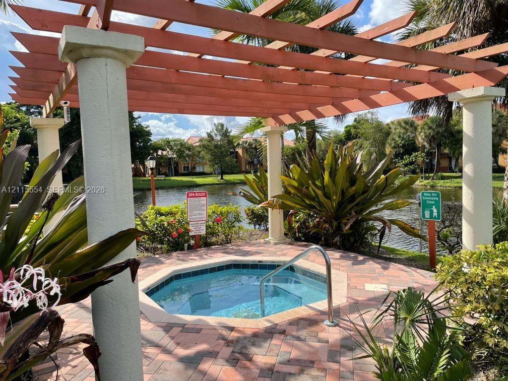 Octagonal spa featuring a brick-paver deck, pergola structure with concrete columns, and integrated stainless steel handrail
