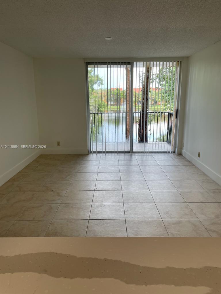 Neutral tile flooring, sliding glass door, and exterior balcony featuring water scenery