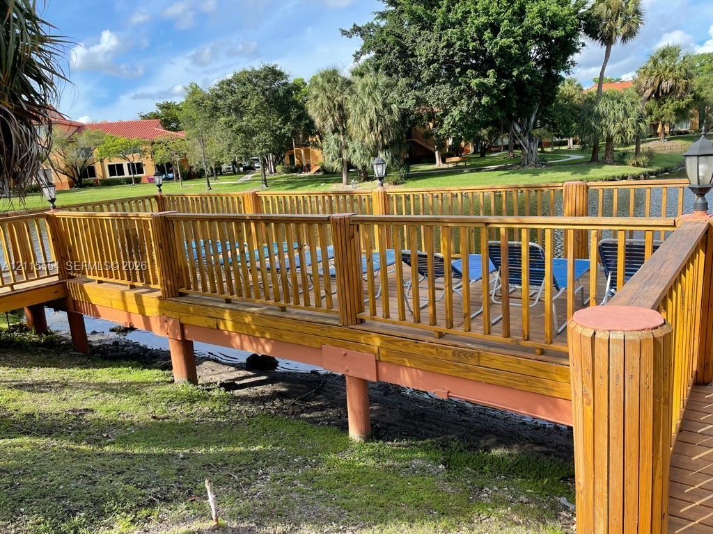 Wood-finished deck featuring perimeter railings, post-mounted exterior lighting, and water-front placement