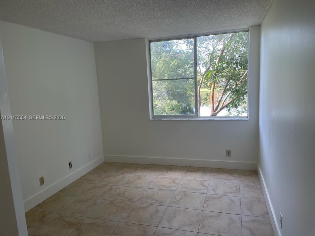 Neutral-toned interior featuring oversized tile flooring, a sliding glass window, and water-front scenery with mature trees