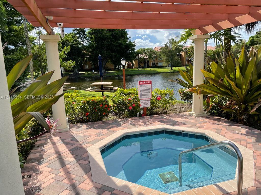 Outdoor spa featuring a concrete paver deck, wooden pergola with structural columns, and metallic handrail