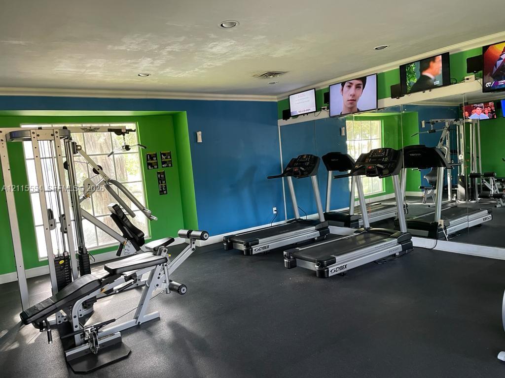 Fitness area featuring recessed lighting, a full-length wall mirror, grid-pane windows, and high-impact rubber flooring
