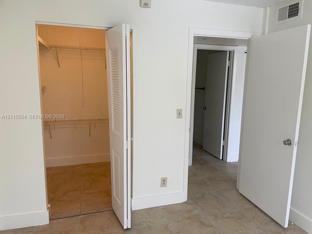 Interior space featuring large-format tile flooring, a walk-in closet with built-in wire shelving, and bi-fold closet doors
