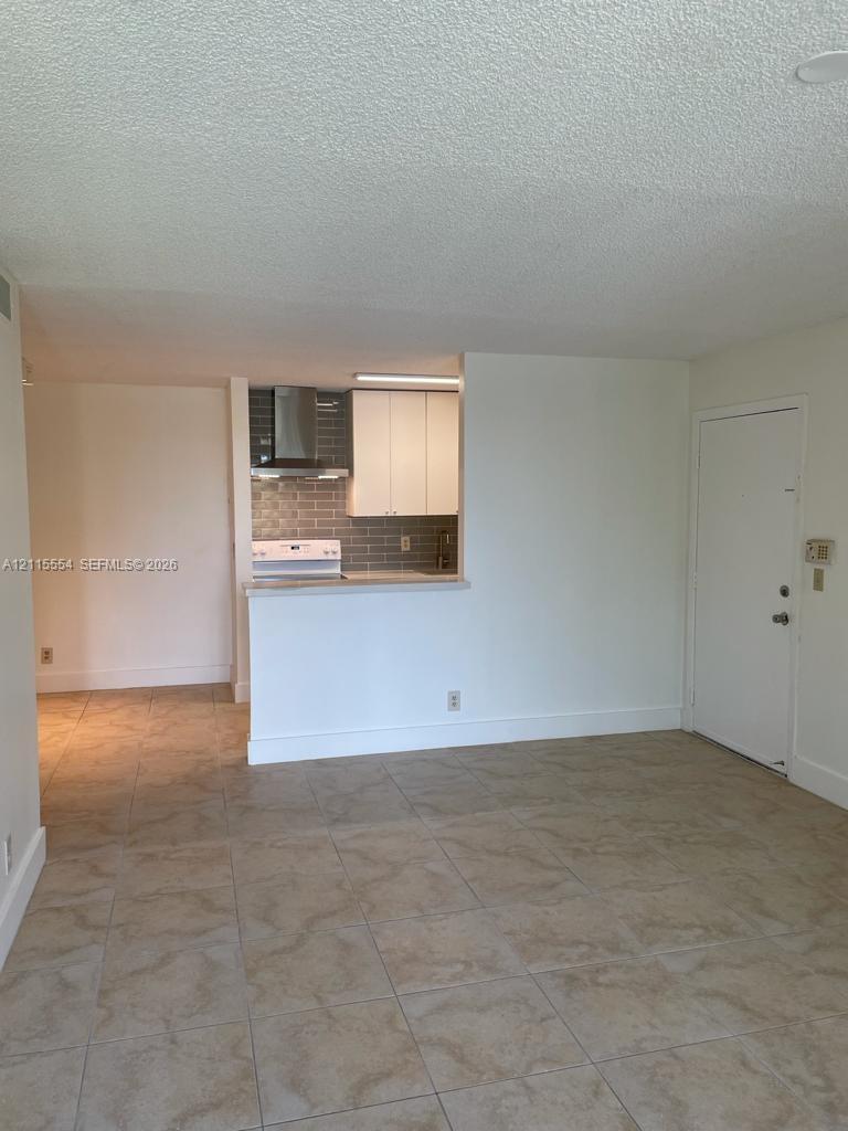 Kitchen featuring white cabinetry, a neutral subway tile backsplash, stainless steel range hood, and tile flooring