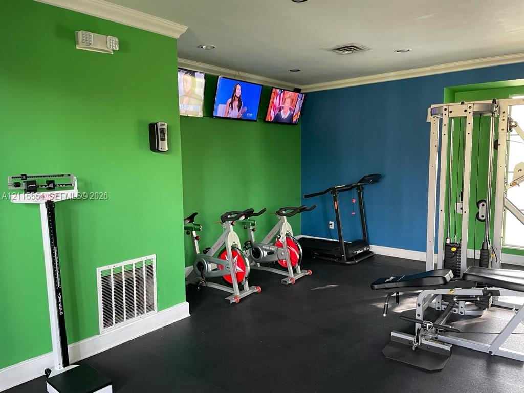 Dedicated fitness space featuring recessed lighting, crown molding, and durable rubber flooring