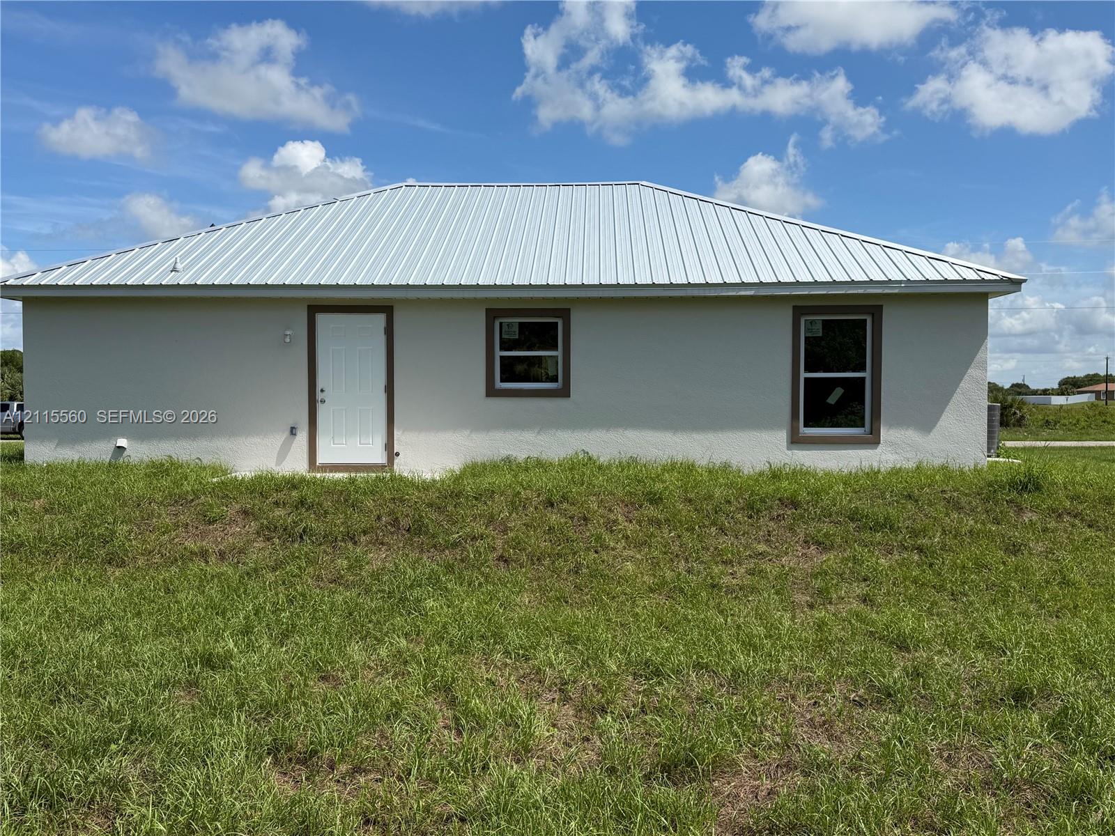 Stucco exterior featuring a metal roof, clean-lined trim, and dual pane windows
