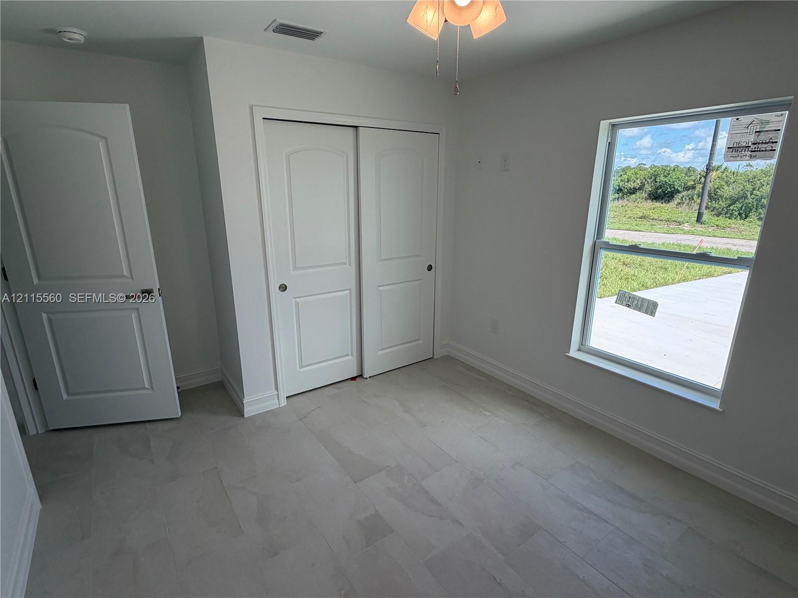 Neutral-toned tile flooring, recessed ceiling light with integrated fan, multi-panel doors, and a window providing natural light