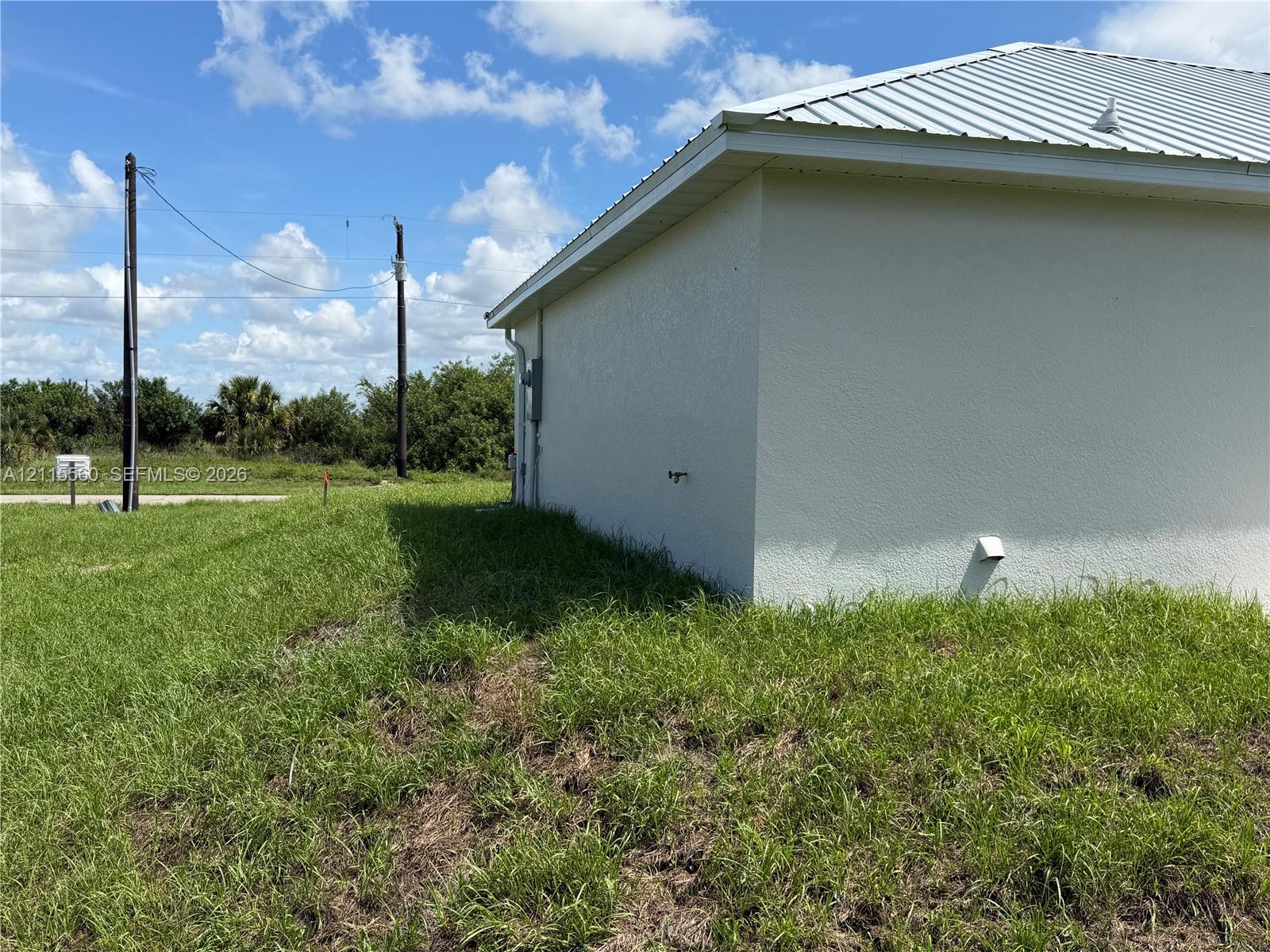 Stucco exterior featuring a metal roof and an expansive lawn