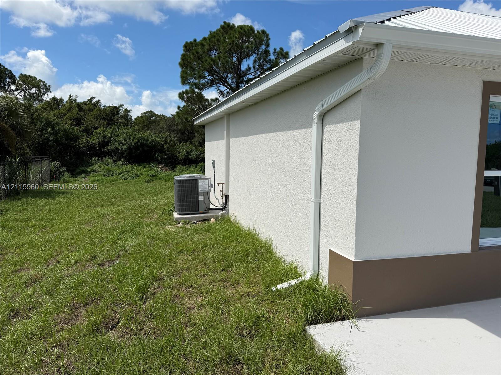 Stucco exterior siding, metal roof, and concrete side patio