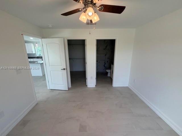 Neutral wall finish with tile flooring, three-panel interior door, and ceiling fan with integrated light fixture
