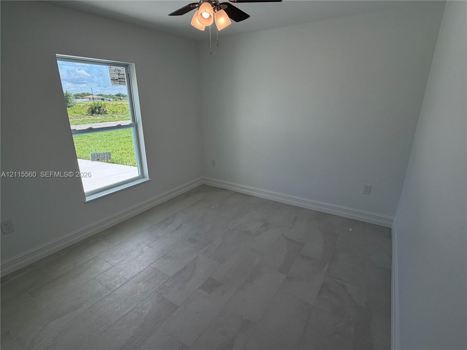 Interior space featuring neutral-toned tile flooring, light-colored wall finishes, a single-hung window, and an attached ceiling fan with multi-light fixture
