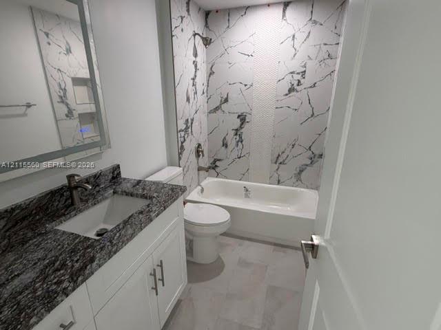 Bathroom featuring a white vanity with stone-finish countertop, undermount sink, illuminated mirror, and a tub-shower combination with floor-to-ceiling patterned wall tile