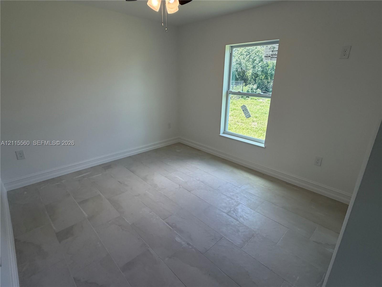 Neutral-toned tile flooring, light-colored walls, single-pane window, and a ceiling-mounted light fixture