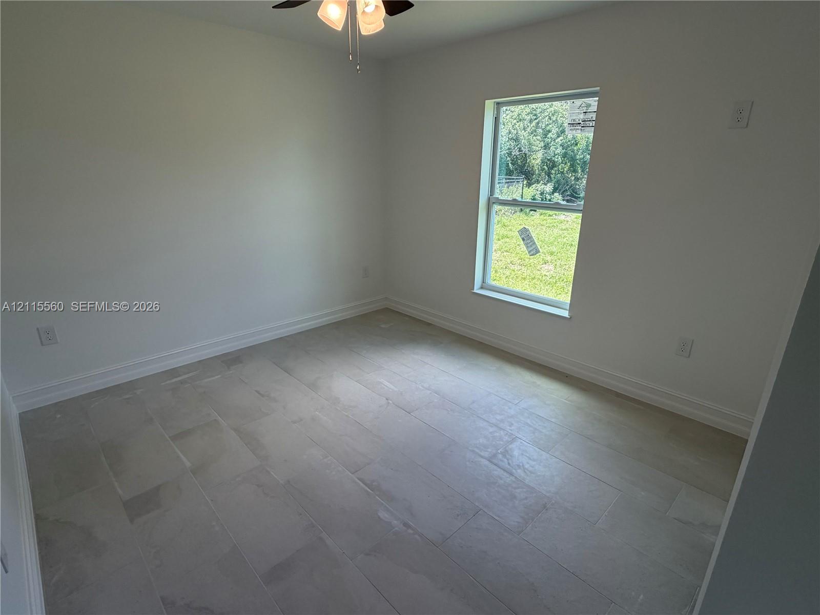 Neutral interior space featuring large-format tile flooring, a single-hung window, and a ceiling-mounted light fixture
