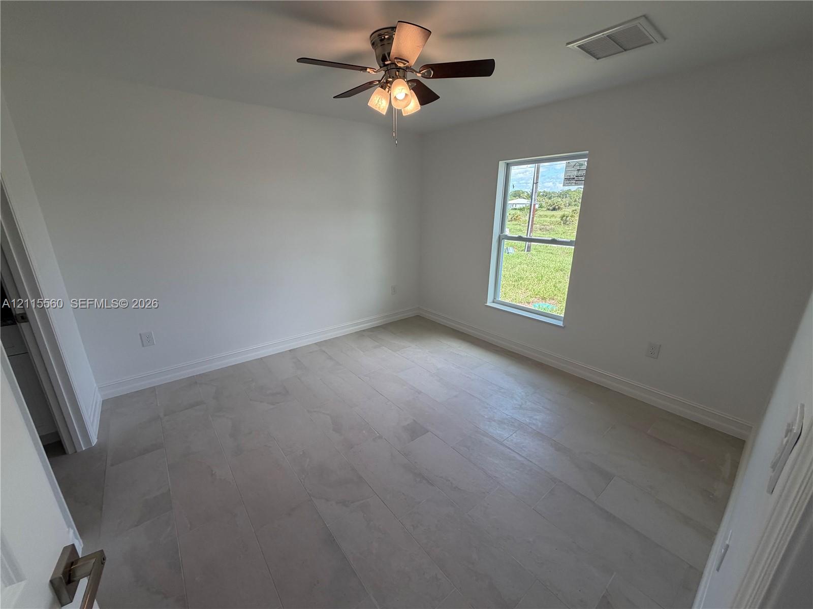 Interior room featuring neutral wall finishes, large-format tile flooring, a multi-light ceiling fan, and a window with exterior exposure