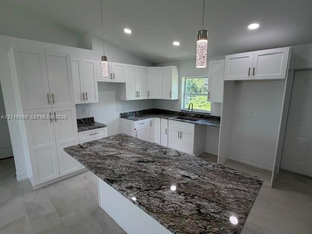 Kitchen featuring white cabinetry, stone countertops, a center island, pendant lighting, and recessed ceiling lights
