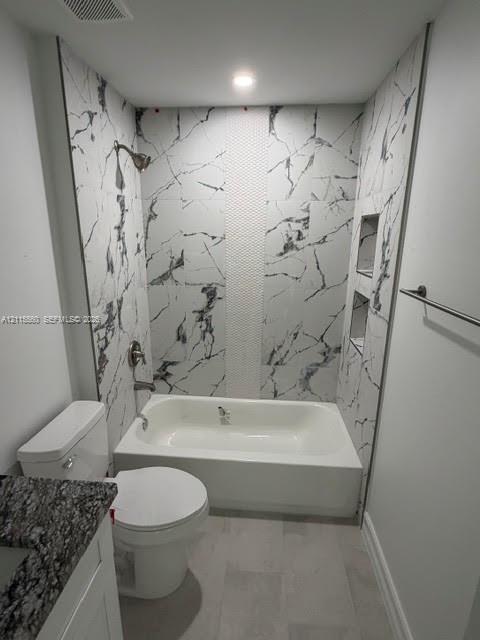 Bathtub surround featuring large-format stone-patterned tile, a vertical textured accent inlay, dual built-in recessed wall niches, and a polished metal shower fixture