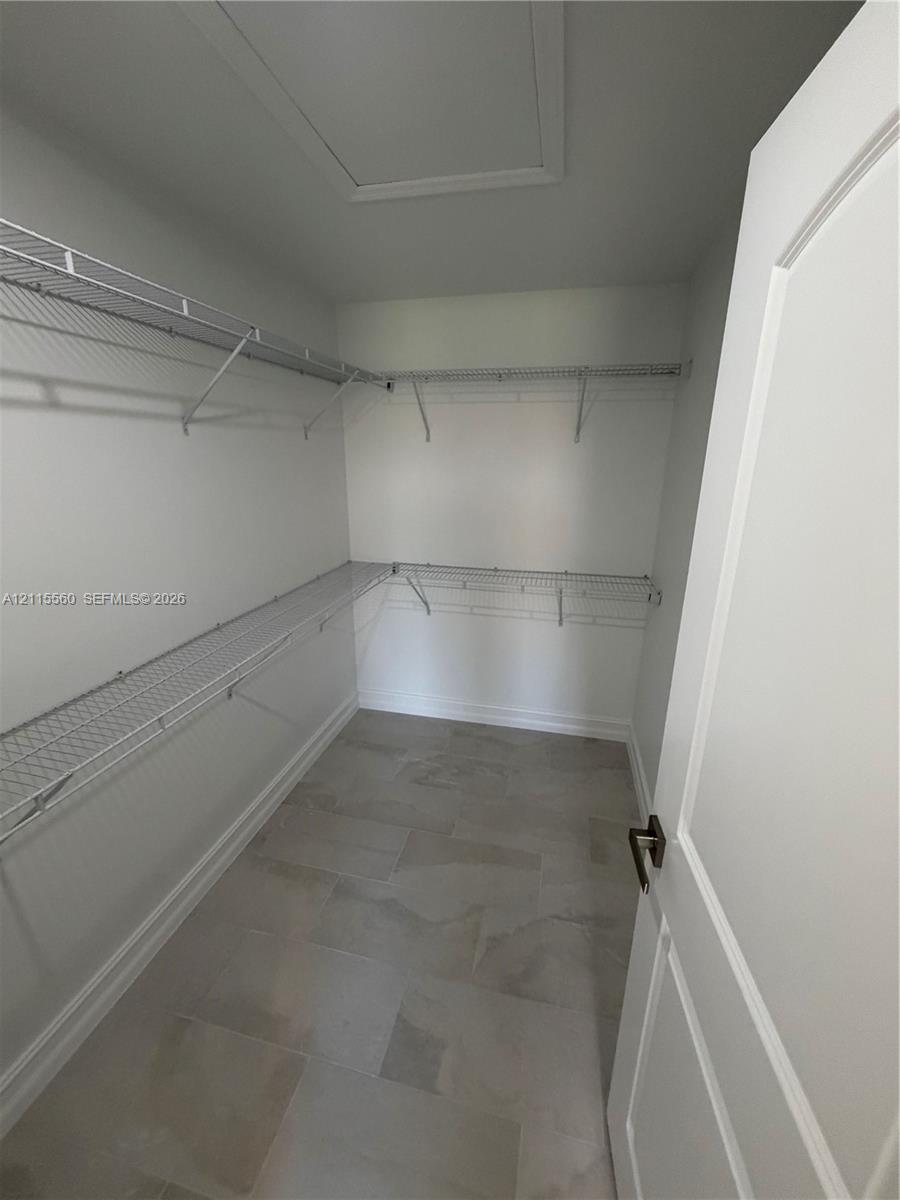 Walk-in storage space featuring multi-level wire shelving and large-format tile flooring