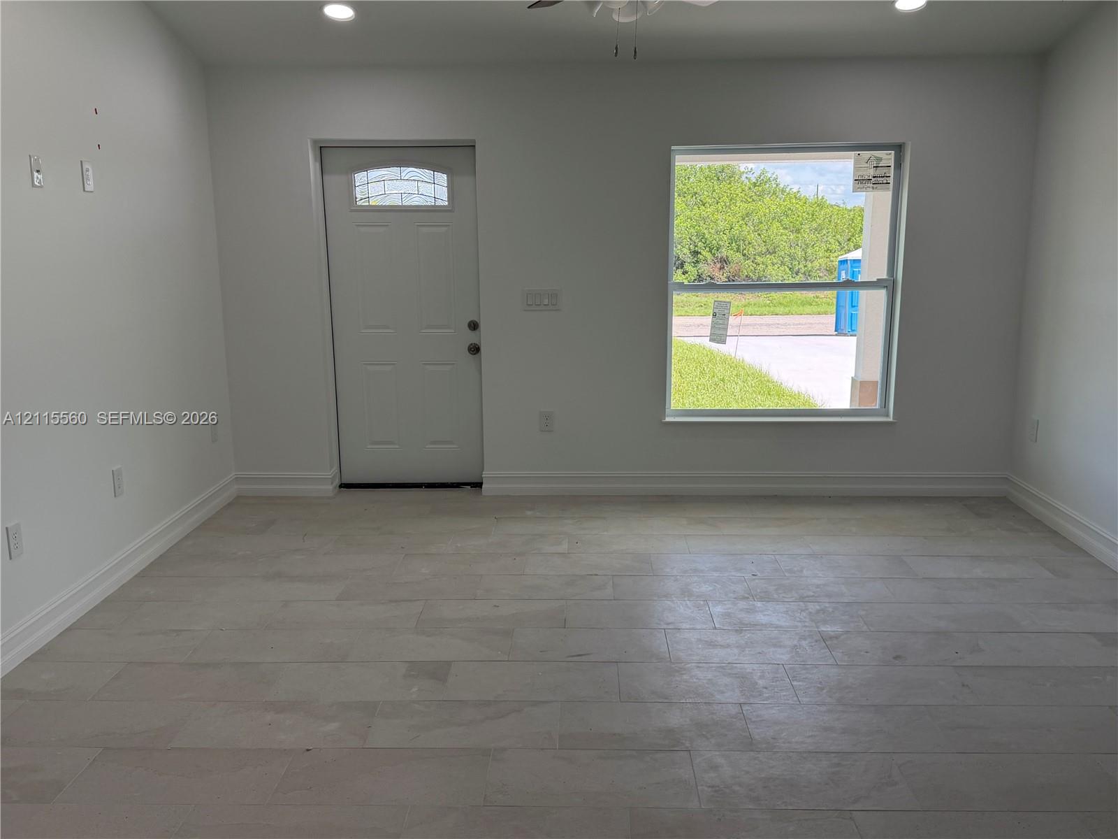 Neutral-toned tile flooring, recessed ceiling lighting, and a single-light glass panel entry door