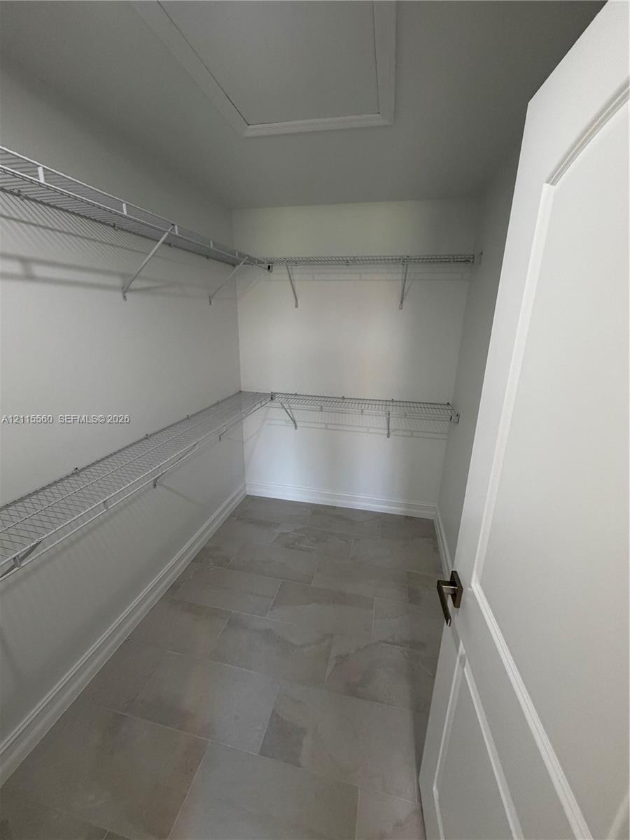 Storage room featuring large-format ceramic tile flooring and multi-level white wire shelving