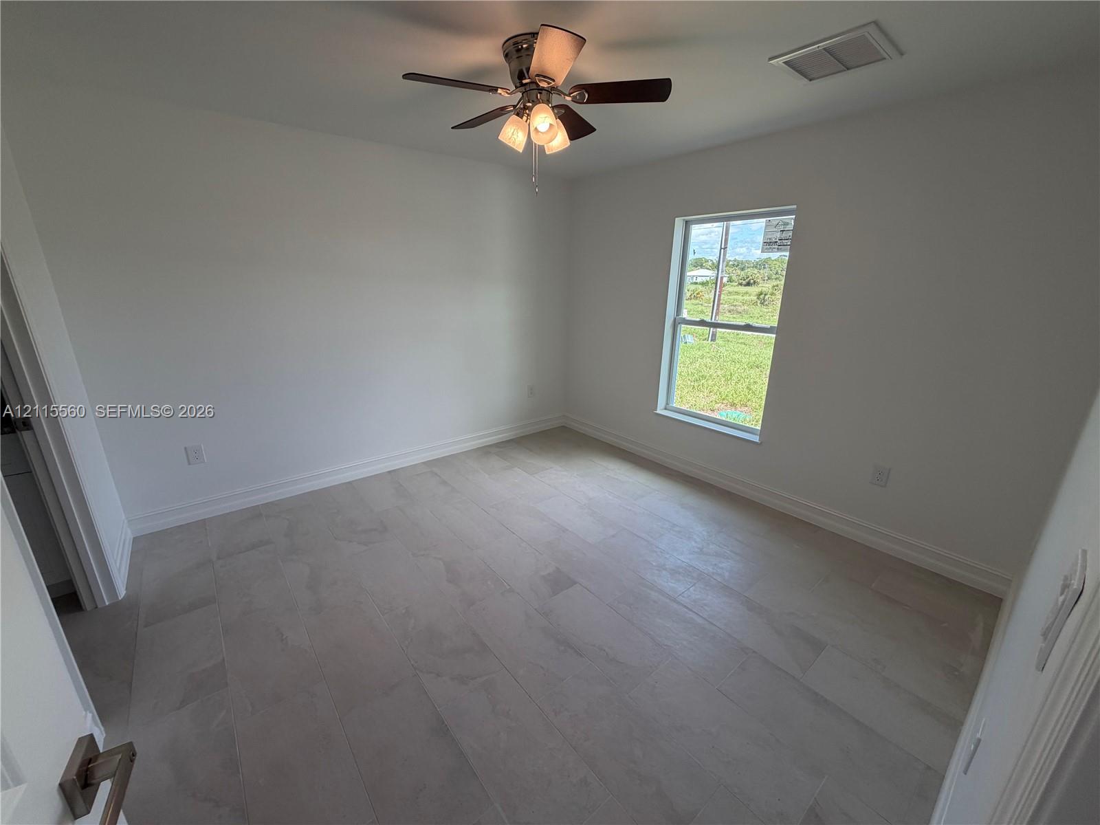 Neutral-toned tile flooring, multi-light ceiling fan, and window featuring exterior natural lighting