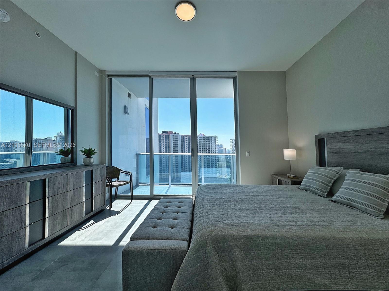 Floor-to-ceiling glass sliding doors, private balcony, wood-finish flooring, and flush-mount overhead lighting