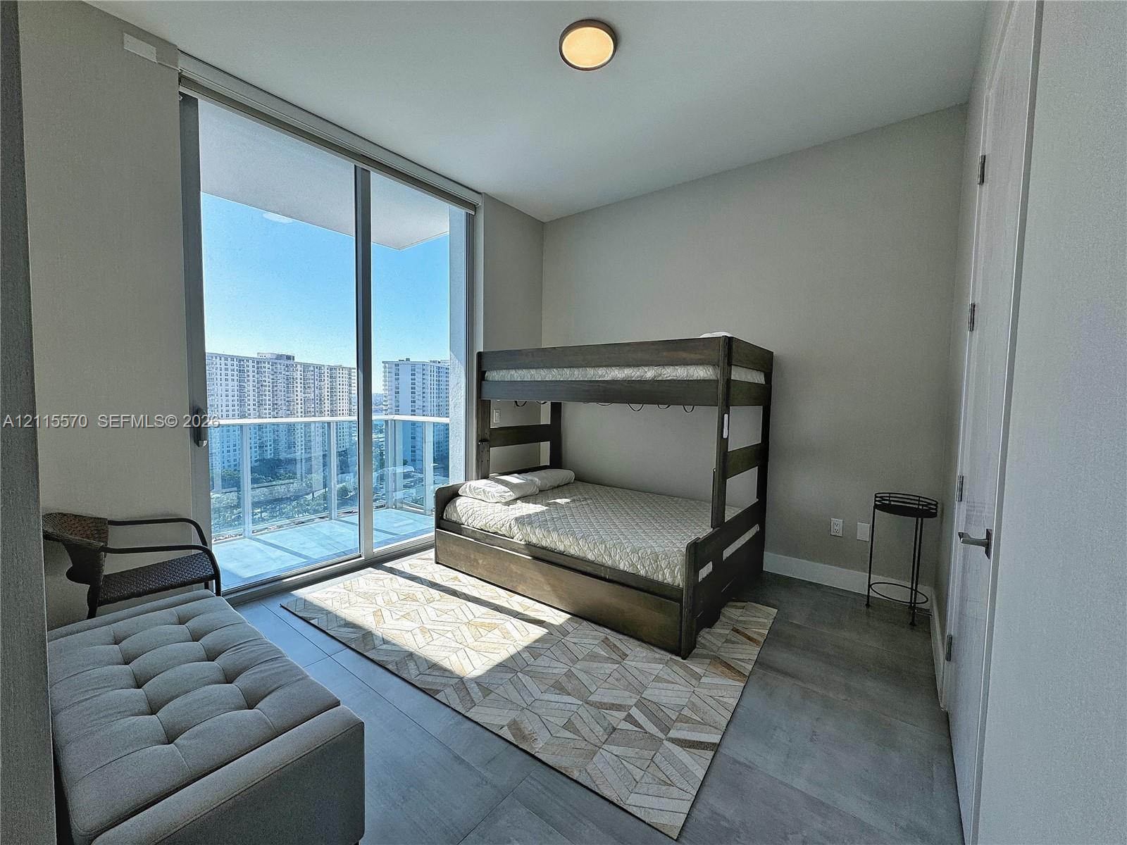 Floor-to-ceiling windows, access to a glass-railed balcony, and large-format tile flooring