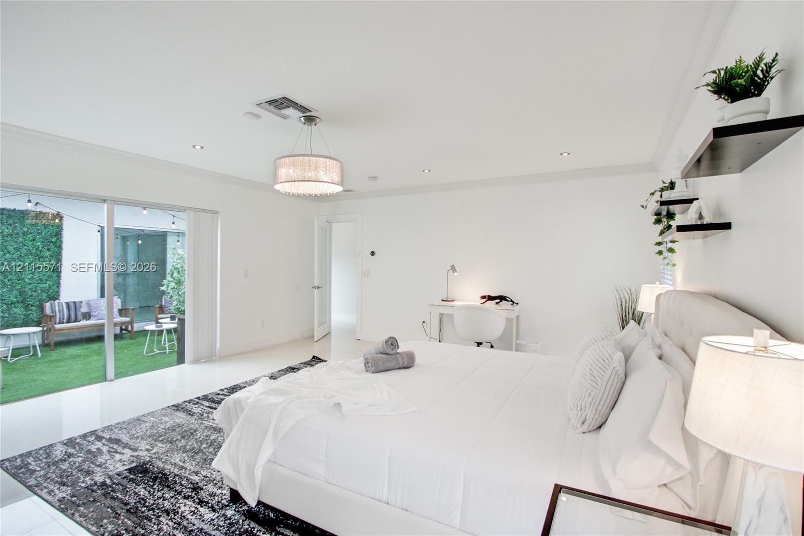 Large room featuring polished stone flooring, recessed lighting, a decorative drum pendant light, sliding glass doors, and built-in floating wall shelving