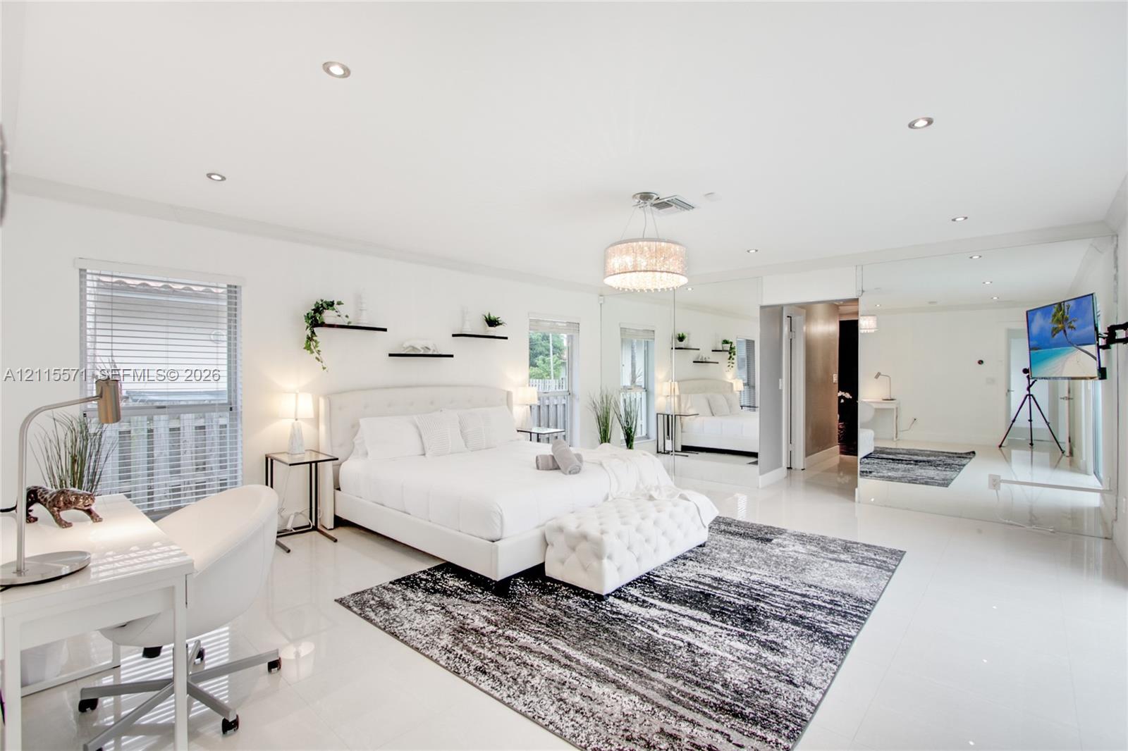 Spacious room featuring polished tile flooring, recessed lighting, a decorative chandelier, and mirrored wall panels