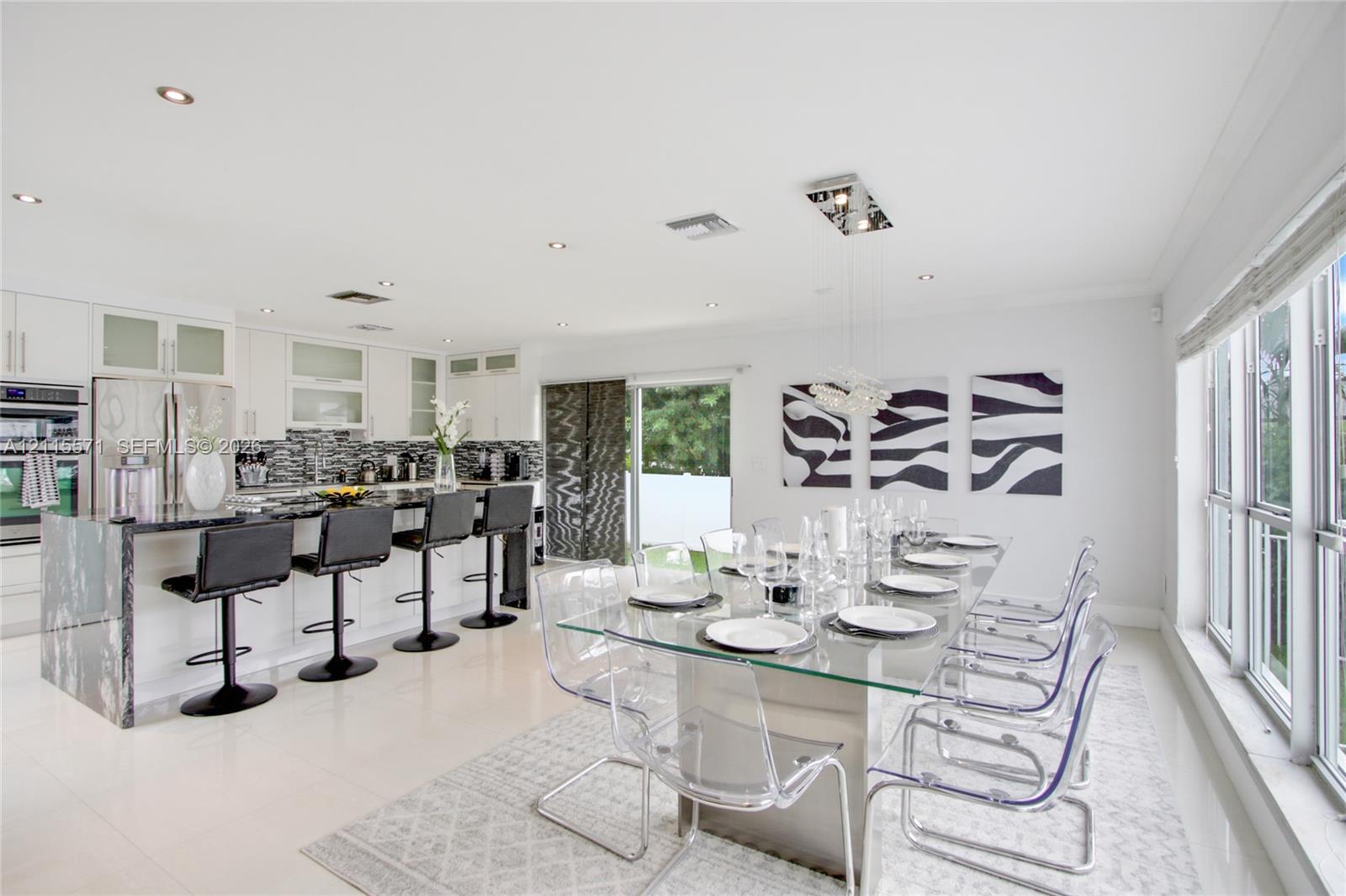 Kitchen featuring white cabinetry, stone-surfaced island with waterfall edge, mosaic tile backsplash, recessed lighting, and large-format tile flooring