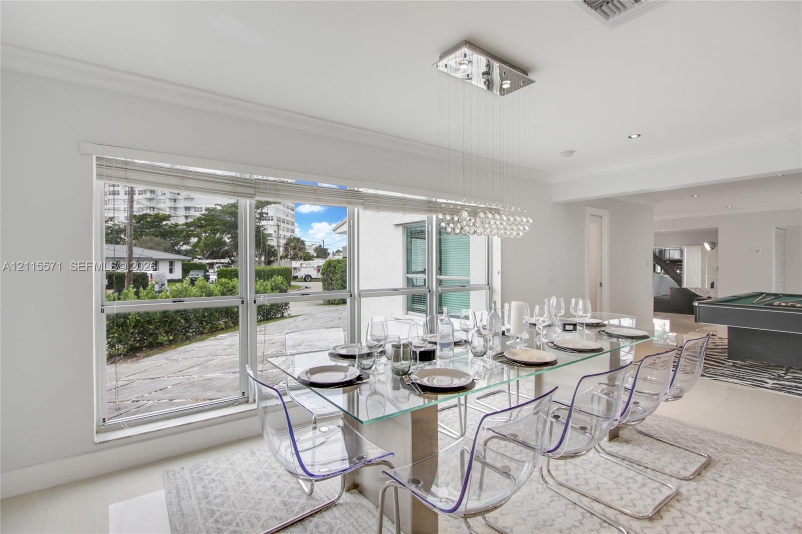 Large picture windows, modern crystal sphere chandelier, recessed lighting, and crown molding