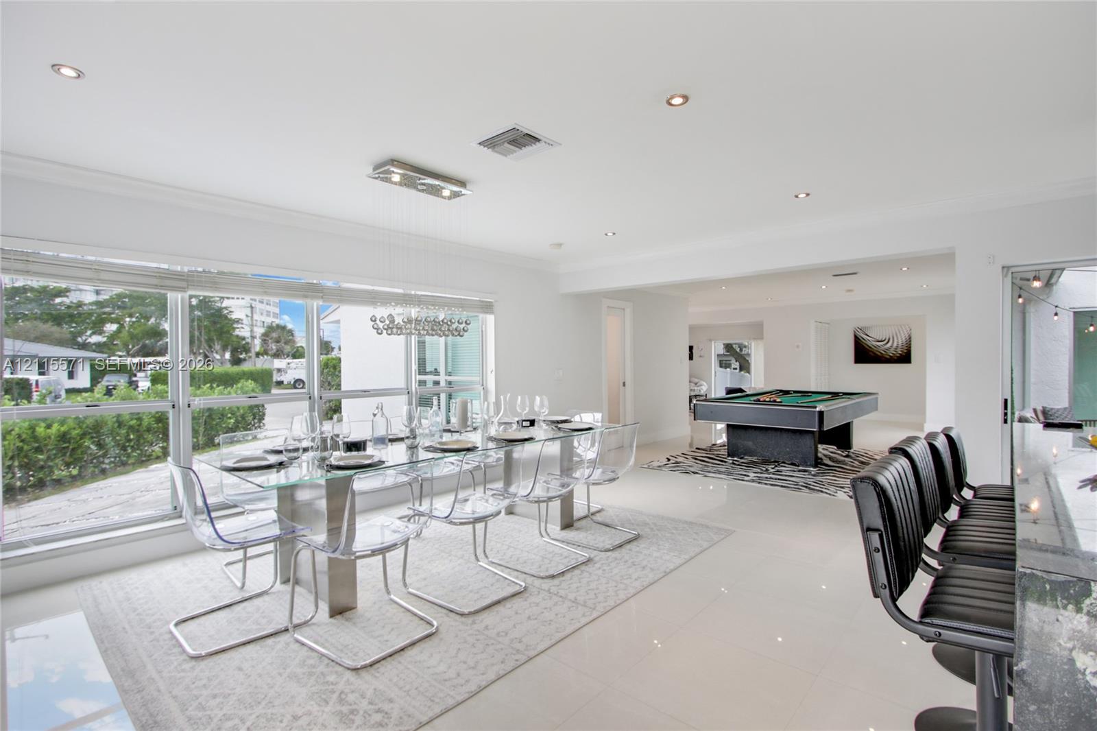 Open-concept floor plan featuring polished tile flooring, recessed lighting, crown molding, and floor-to-ceiling windows