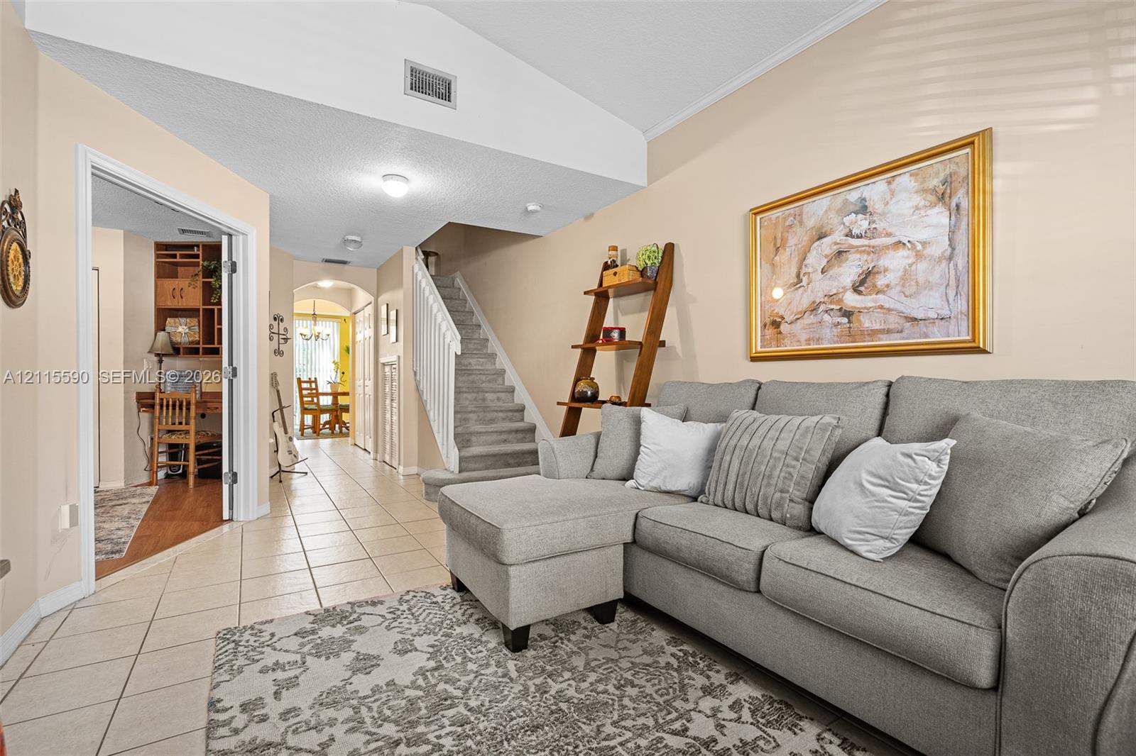 Vaulted ceiling, ceramic tile flooring, and carpeted staircase with white balusters