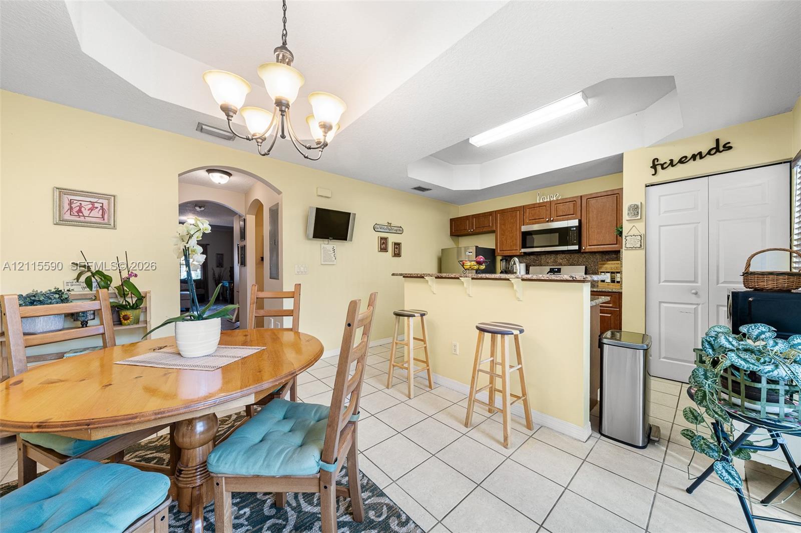 Kitchen featuring a breakfast bar, recessed tray ceiling, tile flooring, and wood cabinetry